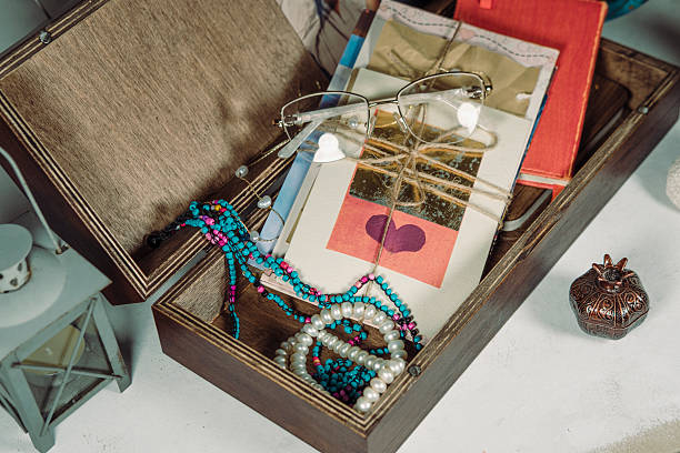 wooden keepsake memory box with old postcards and letters, glasses, colorful handmade seed bead necklace, white cardboard background