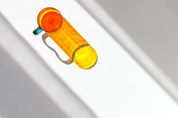 istock One Orange Yellow colored glass cup with beautiful sunlight shadow, long shade on white background. Top view mug for tea and coffee with window shadow, minimal aesthetic top view summer concept 2251501903