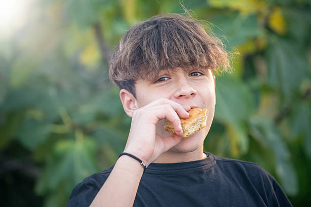 A teenager eats a sandwich. Close-up photo of a mouth without eyes.