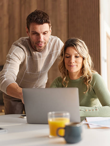 istock Smiling couple working on laptop at dining table. 2251511094