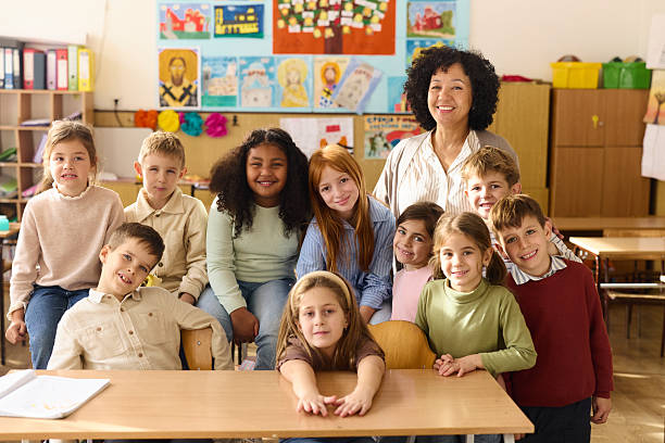 istock Happy female professor with her elementary students in the classroom. 2251512499