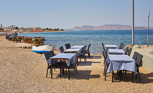 istock Greek beach with traditional blue tables and chairs 2251512655