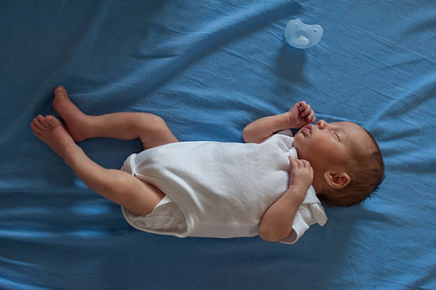istock Newborn baby resting peacefully on a blue sheet with a pacifier nearby 2251512736