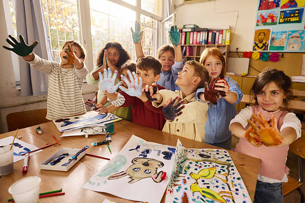 istock Happy elementary students with painted palms on art class at school. 2251513408
