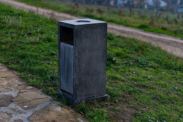 istock Square concrete trash bin placed on a grassy area near a path, ideal for modern parks and urban outdoor settings. 2251515418