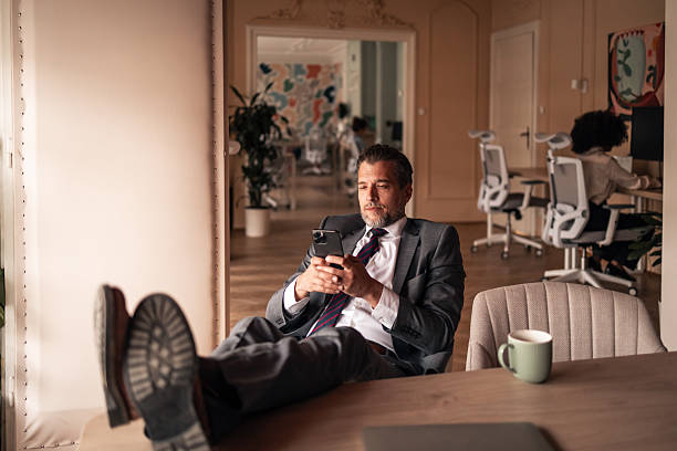 Businessman Relaxing in Office While Using Smartphone