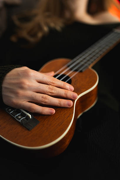 Close up neck of the guitar.White colored wooden ukulele guitar on the yellow background. Hawaiian Four String Guitar. Musical Instrument.