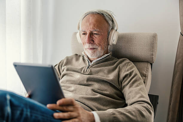 istock Senior man relaxing at home using digital tablet wearing headphones 2251518254