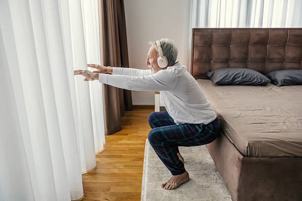 istock Senior man doing squats at home wearing headphones 2251519212