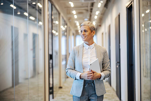 istock Confident businesswoman walking through modern office hallway 2251519461