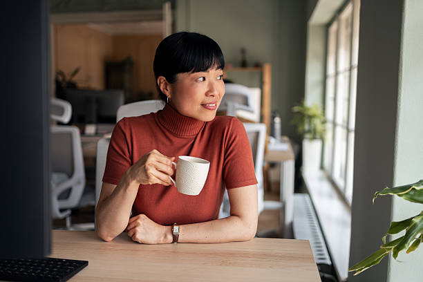 istock Professional Woman Enjoying Coffee at Desk in Modern Office Setting 2251521842