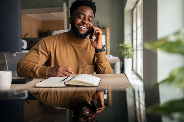 istock Man Smiling While Working on Laptop and Taking a Phone Call 2251522313