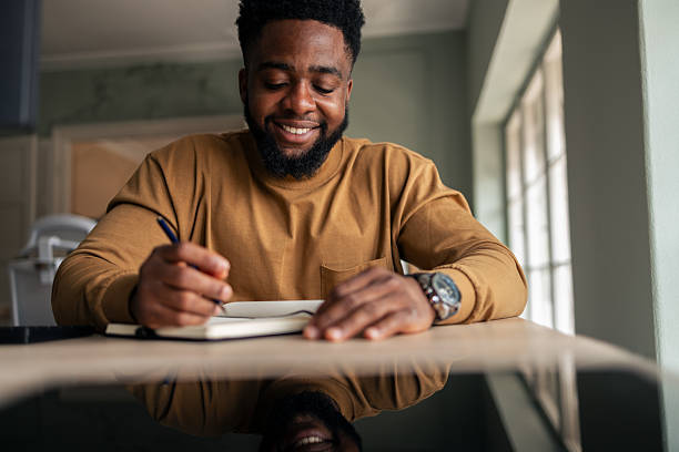 istock Man Smiling While Writing in a Journal at Home 2251522320