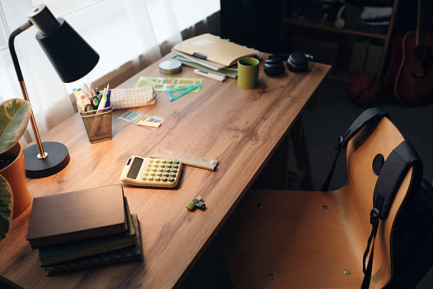 istock Student Desk Displaying Calculator and School Supplies in Lamp Light 2251525357