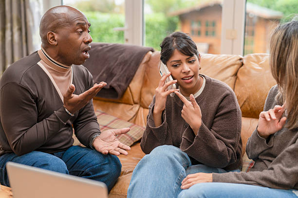 istock Group discussion at home with people talking and using phone in living room setting 2251525591