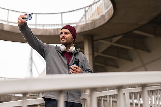 istock Man Taking Smartphone Selfie by Urban Structure in Casual Attire 2251528849