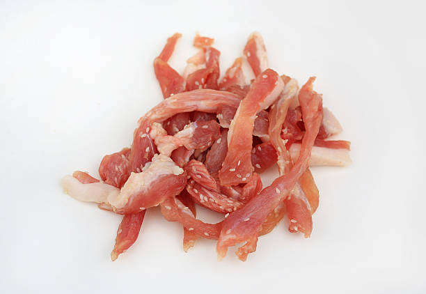 istock Marinated and sliced pork strips, seasoned with sesame seeds ready for sun-drying or grilling, presented on bright white background for food photography. 2251531799