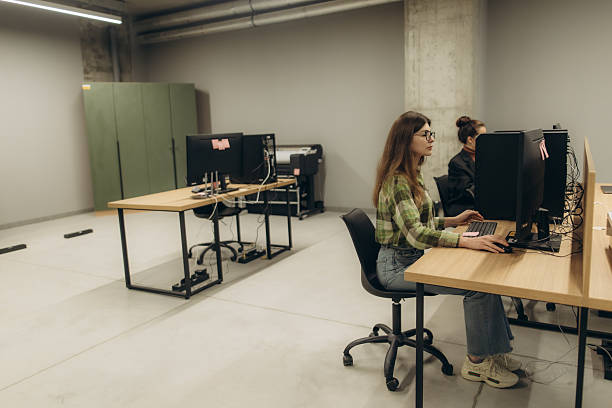 istock Modern Workspace with Focused Individuals Working at Computers in an Industrial Setting 2251533137