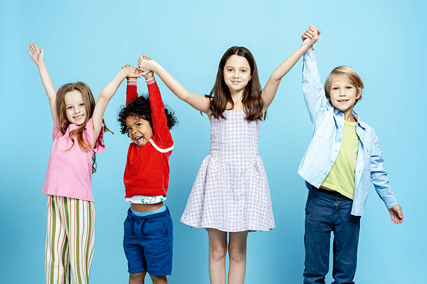 istock Diverse children holding hands, smiling against a blue background, representing unity 2251535537