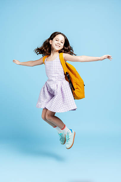 istock Happy elementary age girl student jumping with backpack on way to school 2251535538