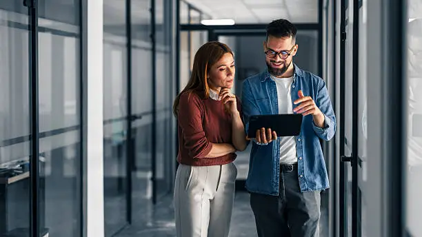 Photo of Two Professionals Discuss Work Using a Digital Tablet in an Office