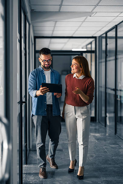 istock Professional Colleagues Discussing Work in a Modern Office Hallway 2251536709