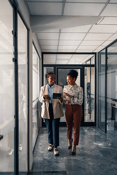 istock Two Professionals Walking and Conversing in a Modern Office Hallway 2251536808