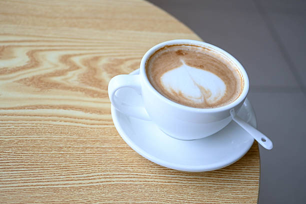 A white coffee cup placed on a brown wooden floor, capturing a minimalist and warm lifestyle moment.