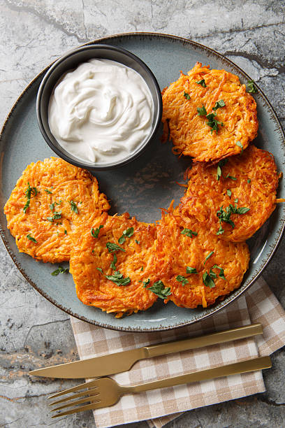 Sweet Potato Hash Browns served with sour cream closeup on the plate. Vertical top view