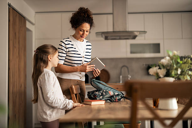 istock Mother Helping Daughter Pack Backpack for School in Modern Kitchen 2251541903