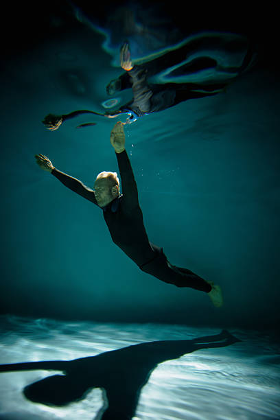 istock Senior free diver in wetsuit swimming in pool with shadow 2251543883