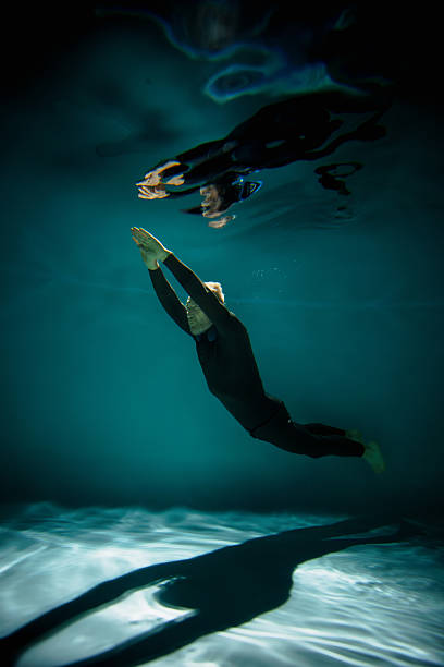 istock Free diver training in swimming pool with reflections on water 2251543890