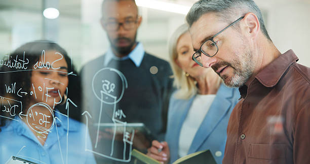 istock Man, group and writing on glass wall at office, planning or insight with risk management solution. Mature person, team and notes on board for problem solving, strategy or feedback at insurance agency 2251544754