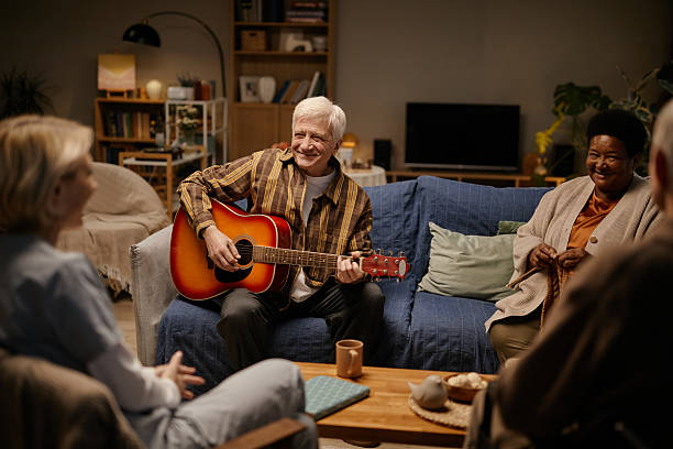 istock Senior Caucasian Man Playing Guitar for Diverse Group in Nursing Home Setting 2251547127