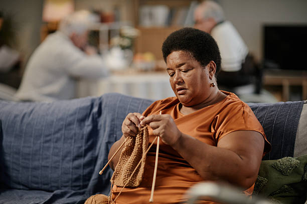 istock Senior Black Woman Knitting While Sitting on Sofa in Nursing Home Setting 2251547278