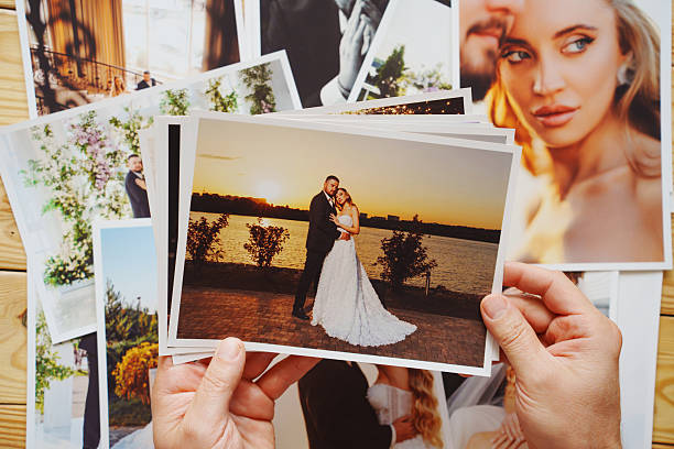 istock Men's hands put on the table and show wedding photos. 2251548293