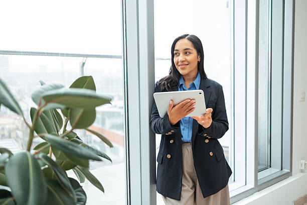 istock Professional businesswoman using digital tablet standing by office window 2251550811