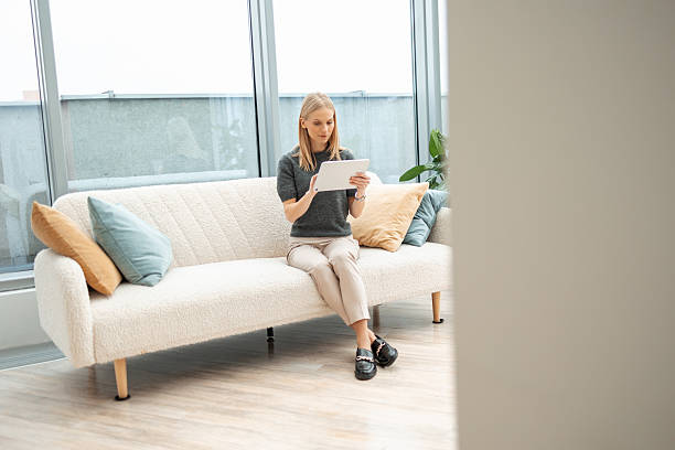 istock Young adult woman relaxing on sofa using digital tablet 2251550812