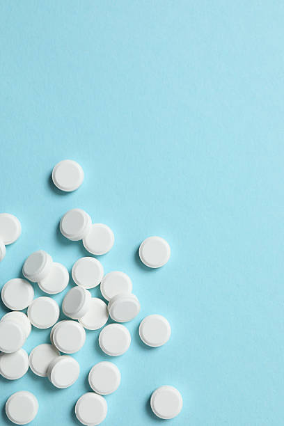 istock White medical pills on a colored background 2251551636