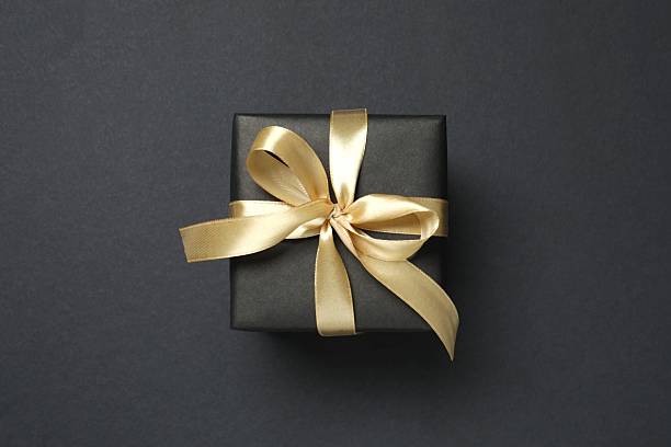 istock Beautiful gift box with a golden bow on black background 2251552291