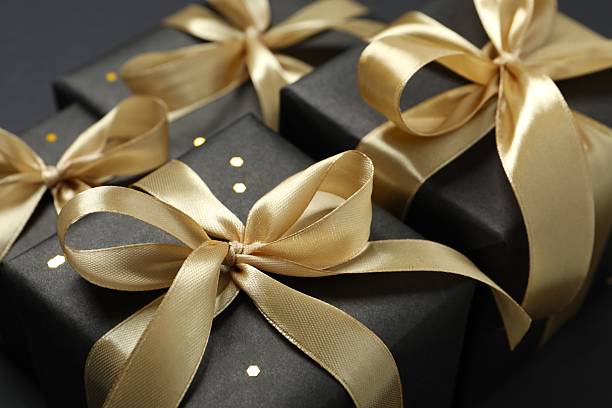 istock Beautiful gift boxes with a golden bows on black background 2251552357