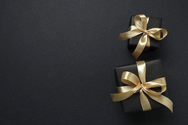 istock Beautiful gift boxes with a golden bows on black background 2251552359