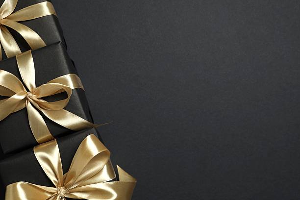 istock Beautiful gift boxes with a golden bows on black background 2251552363