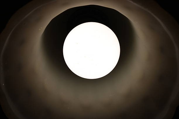 istock Light bulb shines brightly from inside a lampshade in a dark space during evening hours 2251552520