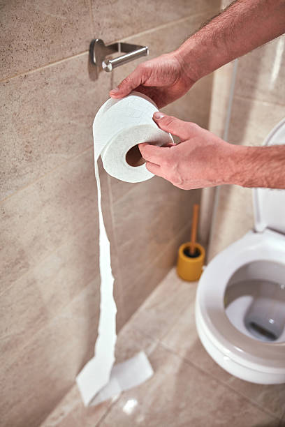 istock Man holding toilet paper roll in the restroom. 2251556436