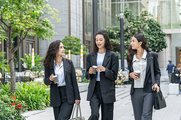 istock Three businesswomen talking and drinking coffee outdoors, showcasing teamwork, communication, and professional collaboration in a modern corporate environment. Ideal for business, leadership, and workplace concepts. 2251563461