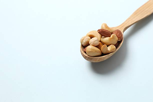 istock Mixed nuts in the spoon. Mix of various nuts on colored background. 2251565726