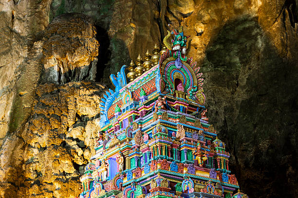 Ornate Hindu temple statues at the entrance of Batu Caves, a famous Hindu temple complex in Malaysia, surrounded by limestone cliffs.