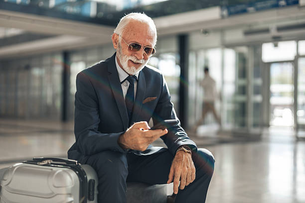 istock Senior Businessman Using Smartphone While Waiting with Luggage 2251566408
