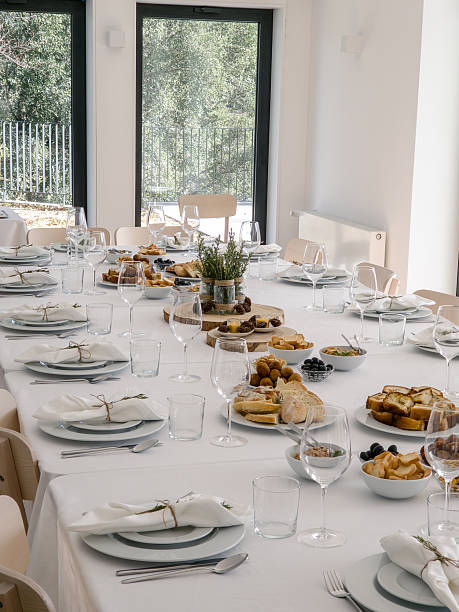 istock A long table in a bright dining room is set for a group gathering, with plates, glasses and a variety of savory appetizers such as bread, meat croquettes, sausage toast, olives and lupin beans arranged for sharing. 2251570541